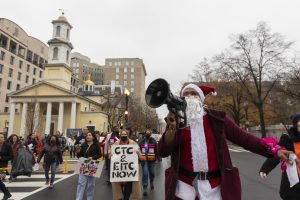 protester in santa suit and crowd with CTC and EITC now signs march to Chamber of Commerce